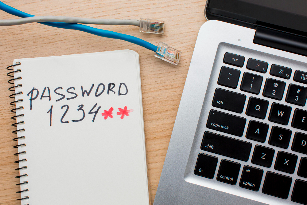 Laptop mit einem Zettel daneben auf dem ein Passwort steht mit den Zahlen 1234